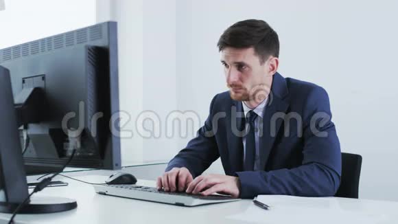 年轻的商人看着一台静止的电脑打哈欠视频的预览图