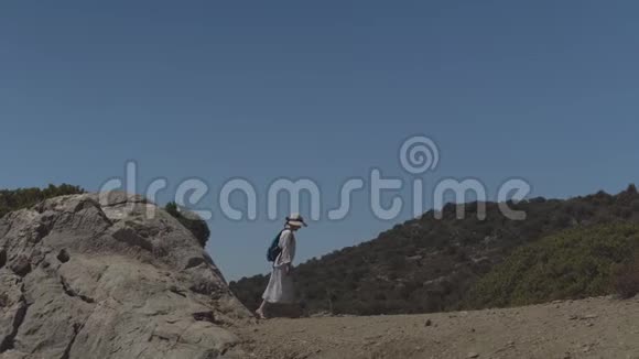 年轻的旅游女孩戴着帽子背着背包在美丽的大自然中漫步视频的预览图