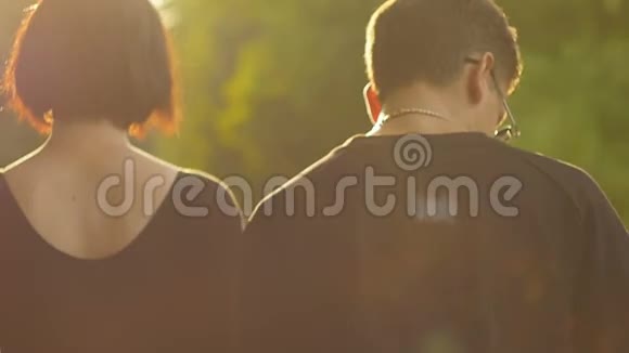 一对年轻的男女在夏天走在桥上日落的光时尚快乐的一对牵手约会视频的预览图