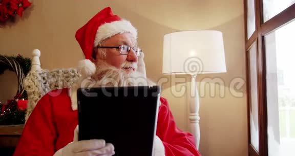 圣诞老人用数码平板电脑透过窗户看视频的预览图