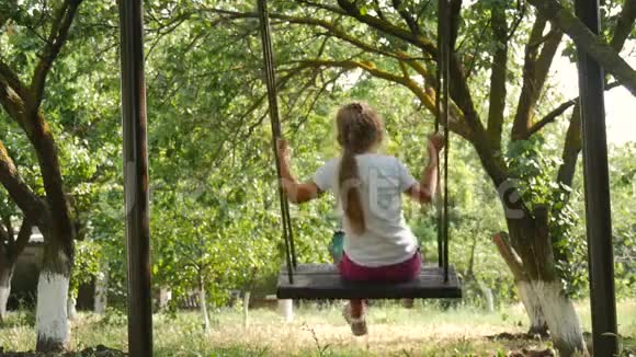 快乐可爱的小女孩在大自然的秋千上摇摆视频的预览图