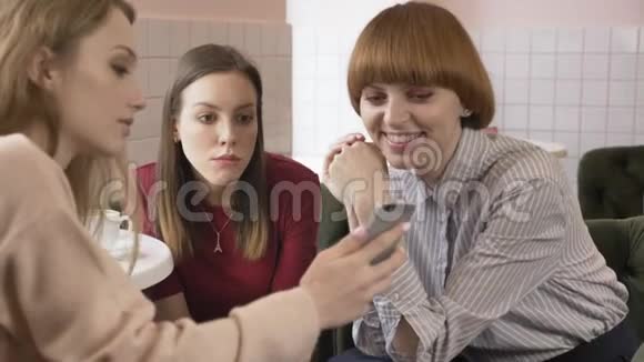 三个年轻的白种人女孩坐在咖啡馆里笑着笑着朋友陪伴闲聊对话讨论视频的预览图