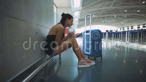 乘客女人坐在机场用电话等着她的航班视频的预览图