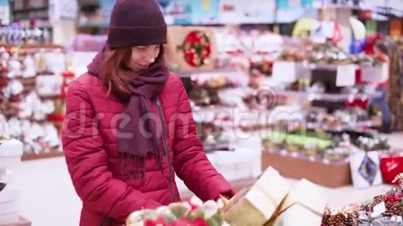 一位年轻的美女在商店里走来走去挑选圣诞装饰品和装饰品来庆祝新年和圣诞节视频的预览图