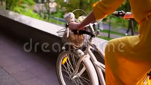 一个不可辨认的女人骑着一辆带篮子和花的城市自行车的特写镜头斯坦迪卡姆慢动作视频的预览图
