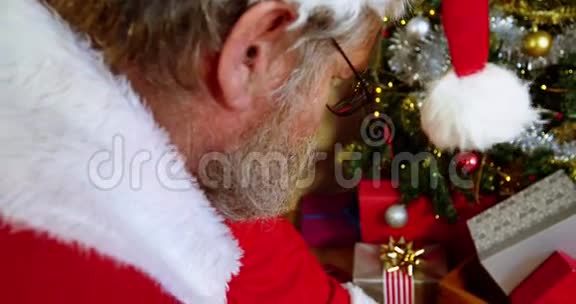 圣诞老人在圣诞树附近放置礼品盒视频的预览图