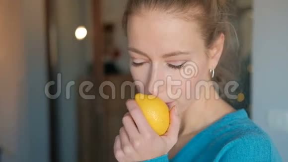 穿着蓝色衬衫的年轻女子吸入新鲜柠檬的香气视频的预览图