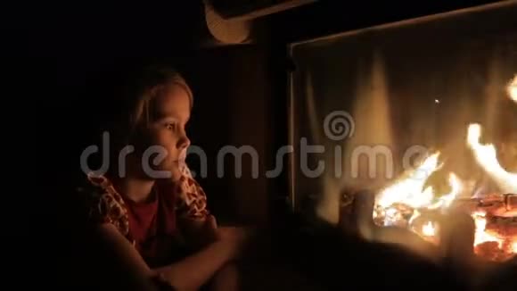 一个悲伤的小女孩坐在壁炉边看着火视频的预览图