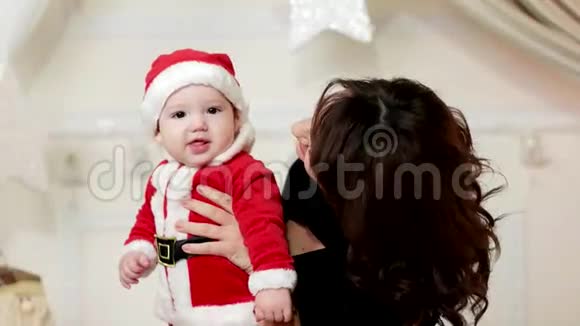 可爱的男孩为母亲微笑小男孩在母亲的手中孩子穿着圣诞老人的狂欢节服装视频的预览图