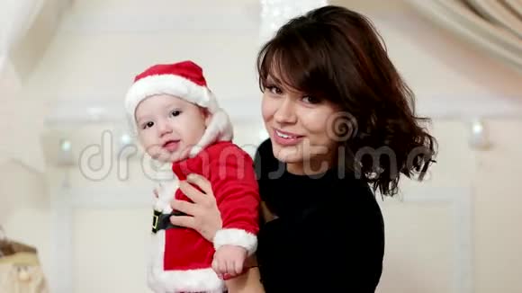 小孩在妈妈的手上小孩穿着圣诞老人的狂欢节服装一个可爱的男孩微笑着妈妈视频的预览图