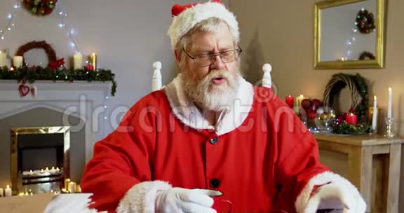 圣诞老人在椅子上放松喝咖啡视频的预览图