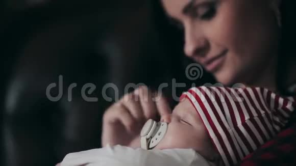 妈妈在圣诞树特写镜头附近亲吻新生婴儿视频的预览图