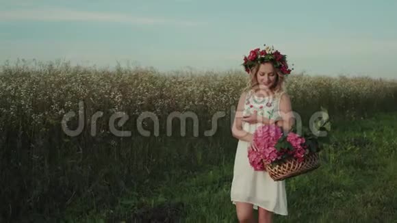 美丽的女孩带着一篮子花在田野里散步视频的预览图