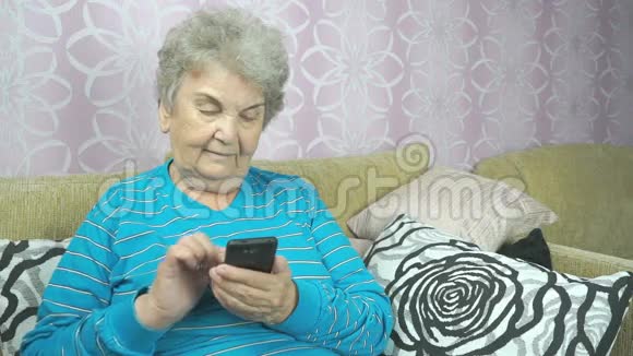 一位使用手机的老太太坐在沙发上视频的预览图