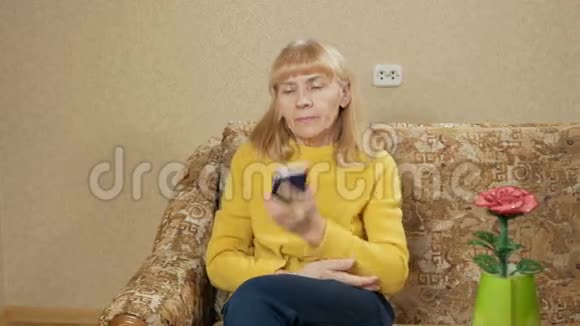 在家里沙发上用手机说话的老女人移动摄像机视频的预览图