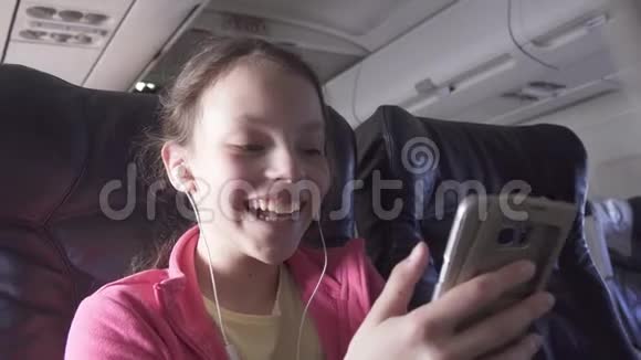 快乐的少女在飞机机舱里玩智能手机游戏还在旅行股票录像视频的预览图