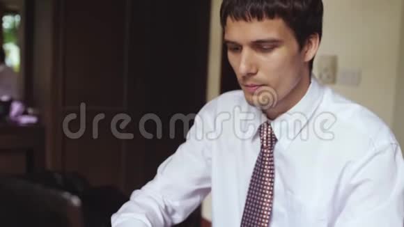 年轻英俊的商人在办公室工作年轻人缓慢地在笔记本电脑上打字3840x2160视频的预览图