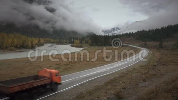 在多云的秋雨天西伯利亚阿尔泰在蜿蜒的河流上行驶的卡车视频的预览图
