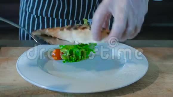 厨师把烤鱼放在盘子里上面有绿色视频的预览图