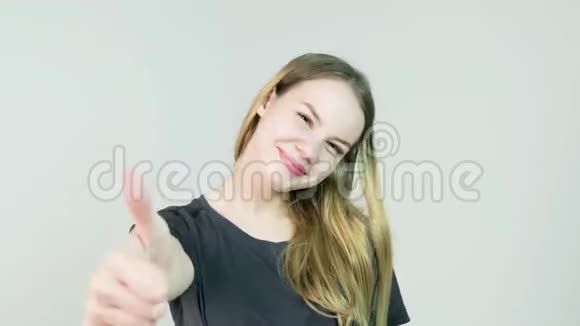 幸福的微笑美丽的年轻女子在白色背景下竖起大拇指视频的预览图