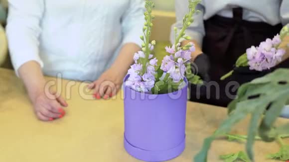花艺师和助理用植物海绵在盒子里制作花艺构图视频的预览图
