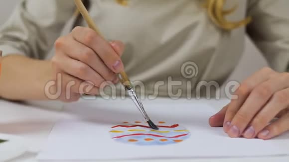 不可辨认的女人在纸上画了一幅色彩鲜艳的素描作为复活节卡片桌子上有一个调色板视频的预览图