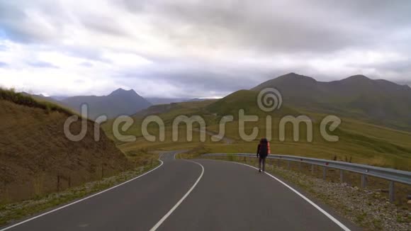 一个人正在高加索山脉的公路旁徒步旅行4K超高清视频的预览图