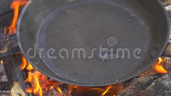 厨师把油倒到煎锅里在篝火上做饭视频的预览图