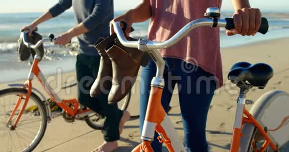 一对骑着自行车在海滩上散步视频的预览图