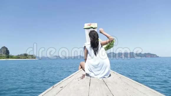 美丽的女人坐在泰国海上的船鼻上举起手背年轻女孩的后视图视频的预览图