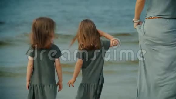 母亲和两个女儿站在沙滩上的水里视频的预览图