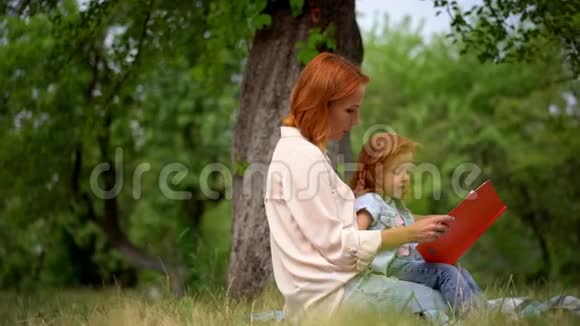 快乐的年轻妈妈带着女儿在户外读书视频的预览图