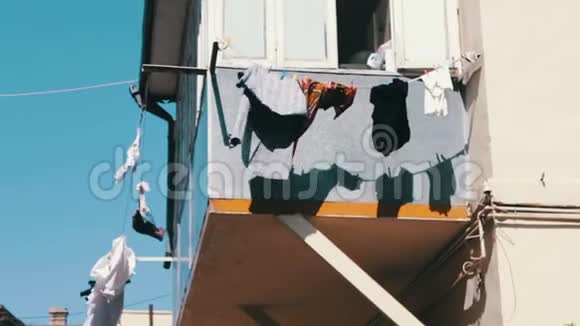 在城市阳光下的绳索上晾干的东西洗过的男人在阳台上的绳子上穿着干燥的衣服一切都在不断发展视频的预览图