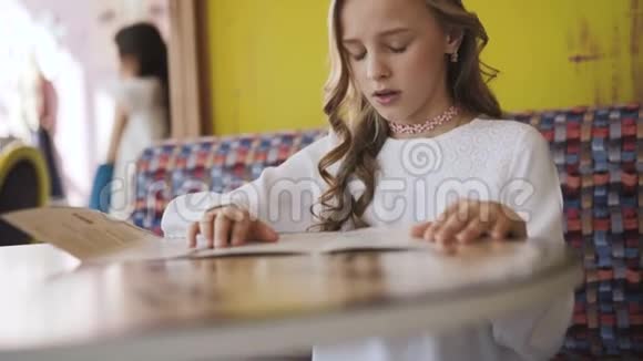 漂亮的微笑的年轻的女孩在咖啡馆里读菜单4K视频的预览图