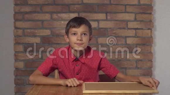坐在书桌前的孩子拿着一张挂图在背景红砖墙上刻着yea视频的预览图