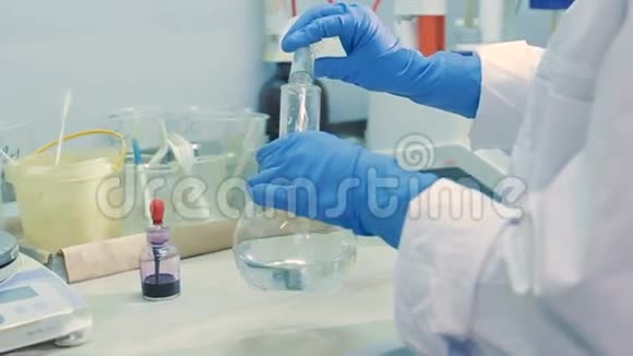 实验室助理在明亮实验室的法兰中混合试剂视频的预览图