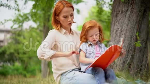 快乐的年轻妈妈带着女儿在户外读书视频的预览图