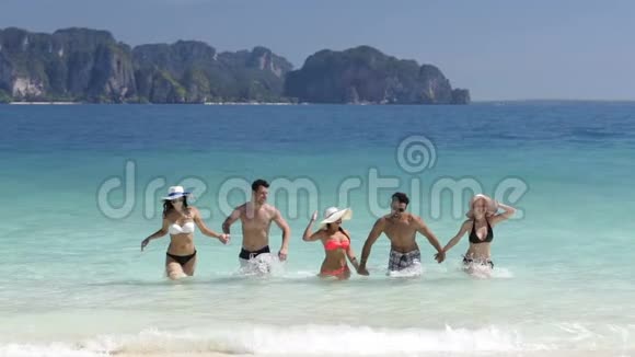 人们在海上度假时从水中手牵手的沙滩上奔跑男人和女人的团体朋友视频的预览图