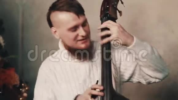 年轻的蓄胡子音乐家莫霍克在玩长角的弦视频的预览图