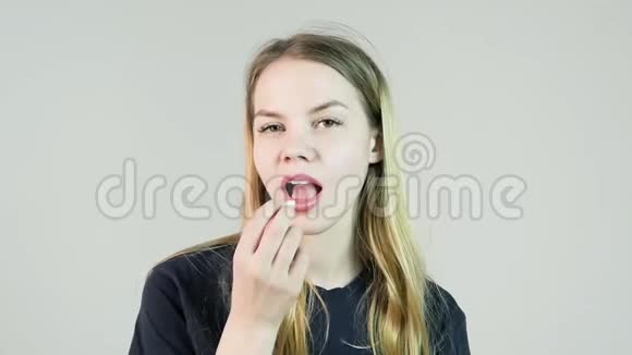 年轻迷人的微笑女人在白色背景上嚼口香糖视频的预览图