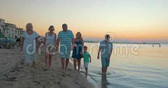 希腊比雷埃夫斯海上夕阳背景下一家人在海滩上散步视频的预览图
