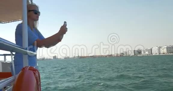 女孩乘船在希腊塞萨洛尼基市海上旅行并拍摄海景视频的预览图