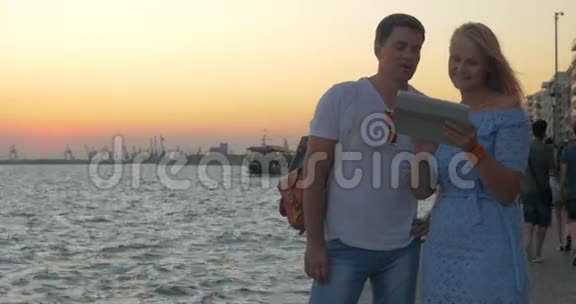 日落时分年轻夫妇在希腊塞萨洛尼基的海滨散步视频的预览图