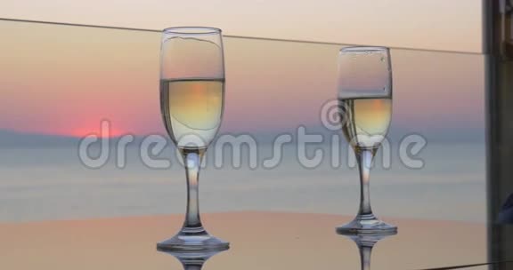 女人和男人的手在夕阳的海洋背景上紧握着一杯香槟近距离观看视频的预览图