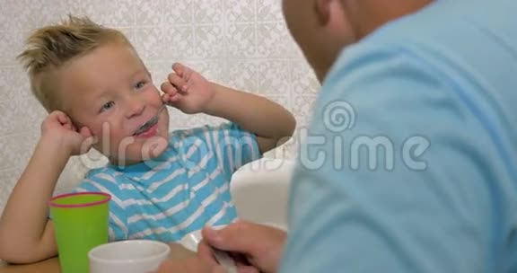 儿子和父亲说话用勺子吃饭微笑着视频的预览图