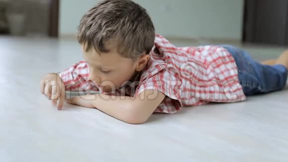 一个伤心的小男孩白天躺在家里的地板上视频的预览图