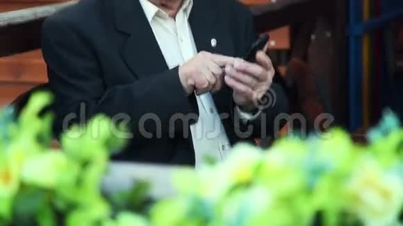 有小玩意的老年人咖啡馆里的爷爷害羞地使用智能手机视频的预览图