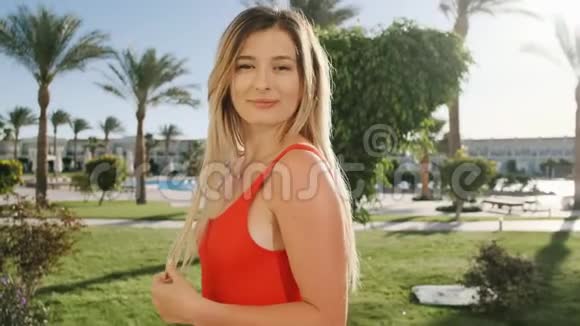 微笑的年轻女孩的肖像看着相机美丽的女人穿着红色的泳衣在炎热的晴天暑假假期视频的预览图