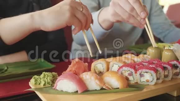 一对拿着筷子的年轻夫妇在日本餐馆的盘子里吃寿司视频的预览图