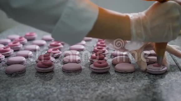 糖果店法国马卡龙的装饰一家手套糖果店的工作人员把奶油和浆果添加到准备好的食品中视频的预览图
